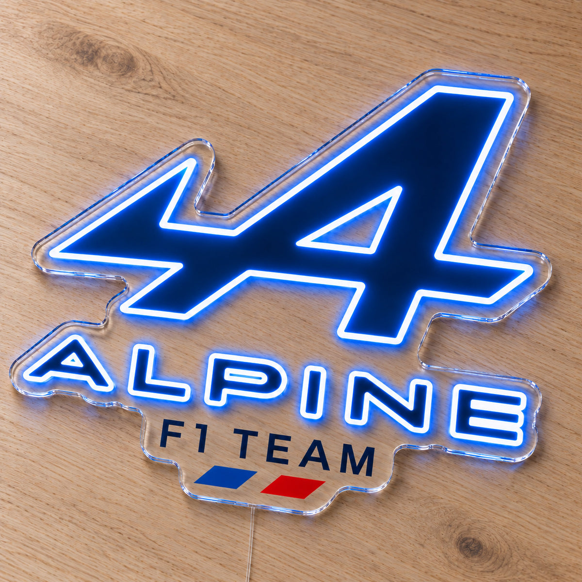 Alpine F1 LED Neon Sign, featuring team logo displayed on a wooden surface.