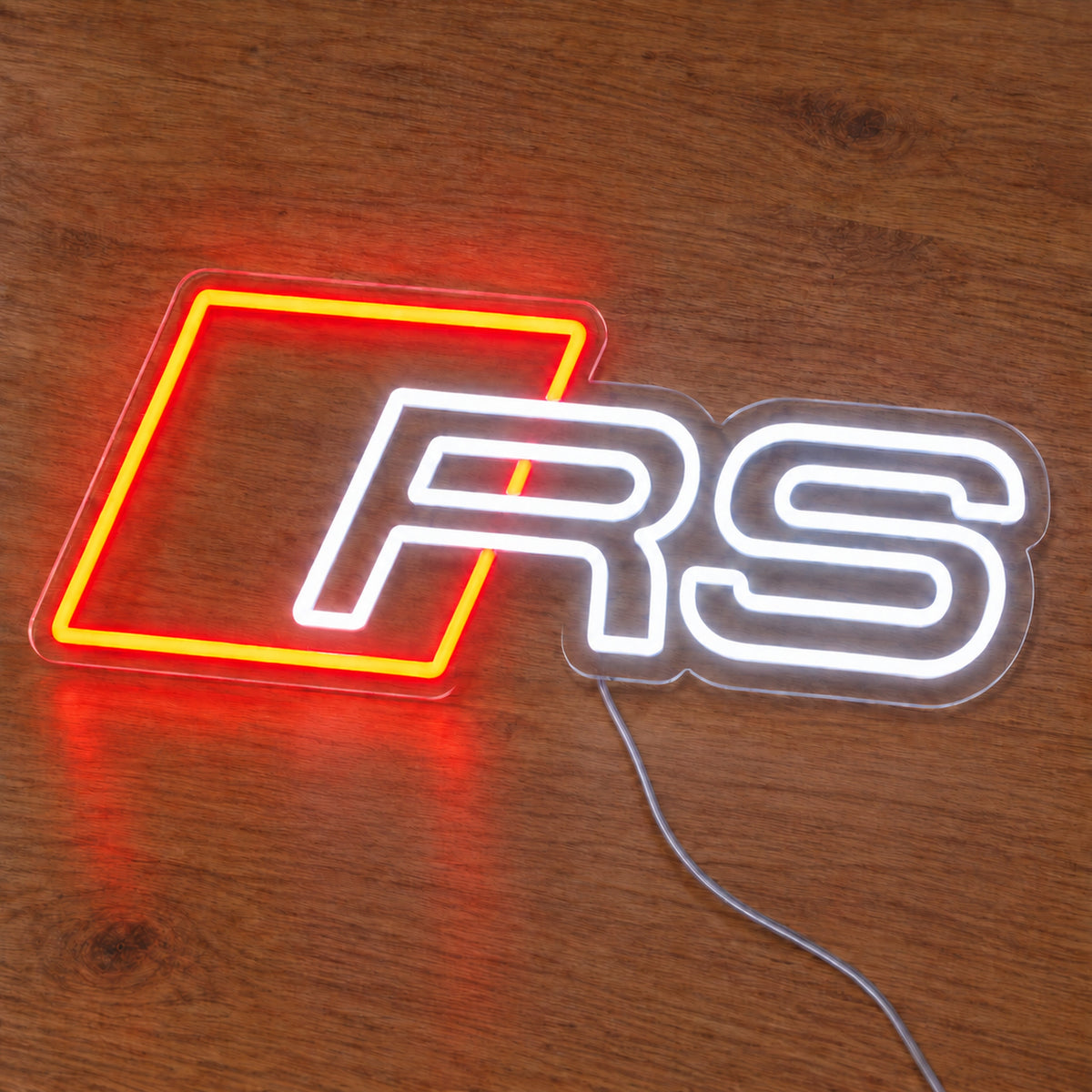 Audi RS LED Neon Sign in red and white, featuring Audi RS emblem on a wooden surface.
