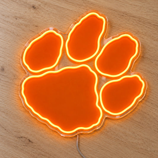 Clemson Tigers Paw LED Neon Sign, featuring team logo displayed on a wooden surface.