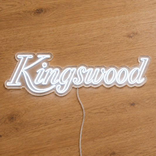 Holden Kingswood LED Neon Sign in white, featuring Kingswood script lettering on a wooden surface.