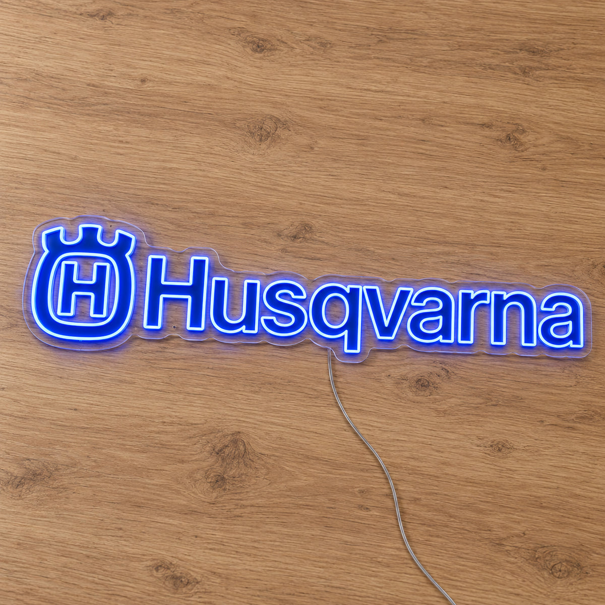 Husqvarna LED Neon Sign, featuring illuminated vehicle logo on a wooden surface.