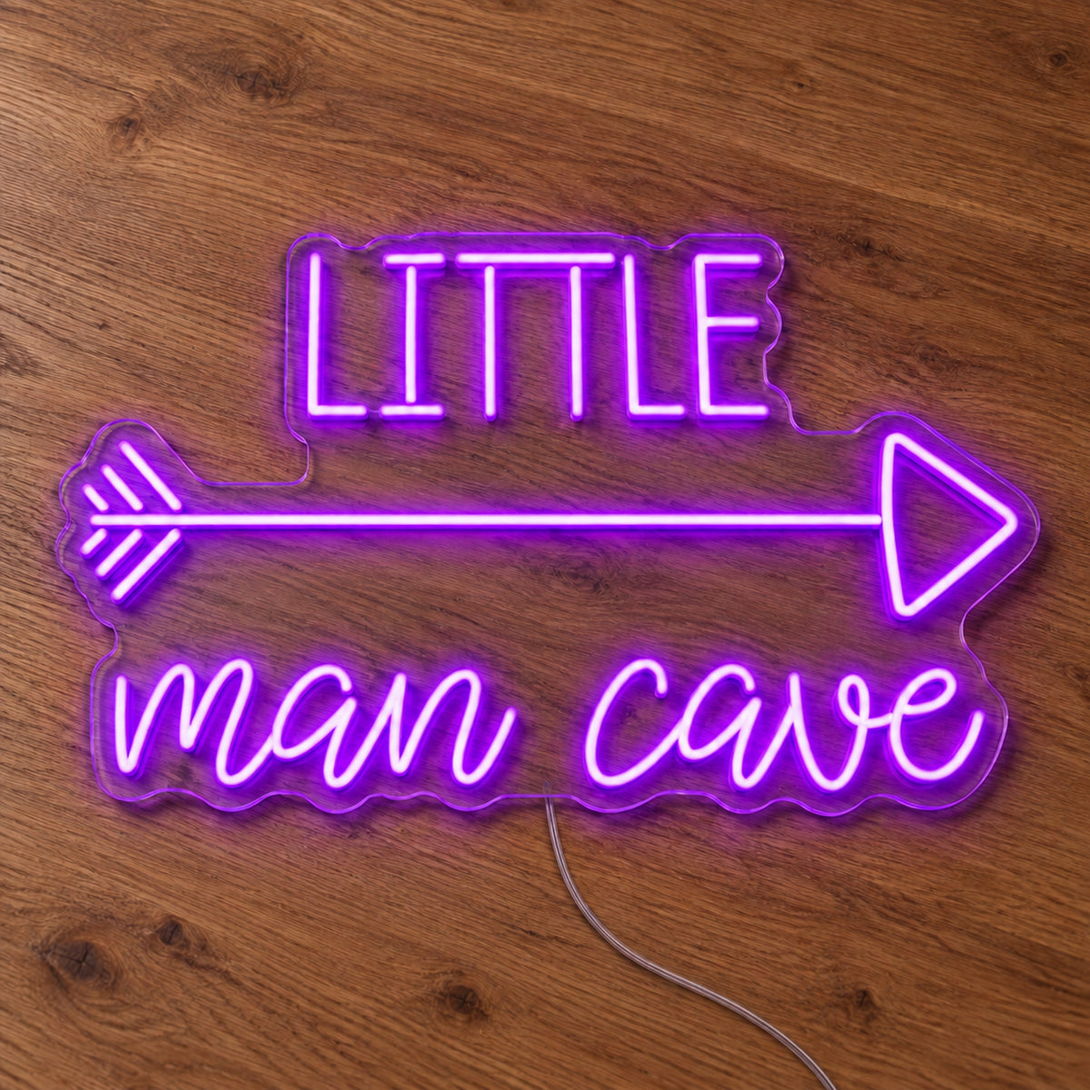 Little Man Cave LED Neon Sign in purple, featuring Little Man Cave lettering with an arrow on a wooden surface.