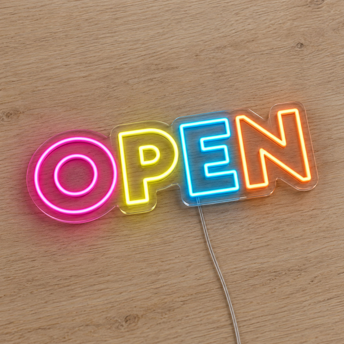 Multicolour Open LED Neon Sign in pink, yellow, blue and orange, featuring Open lettering on a wooden surface.