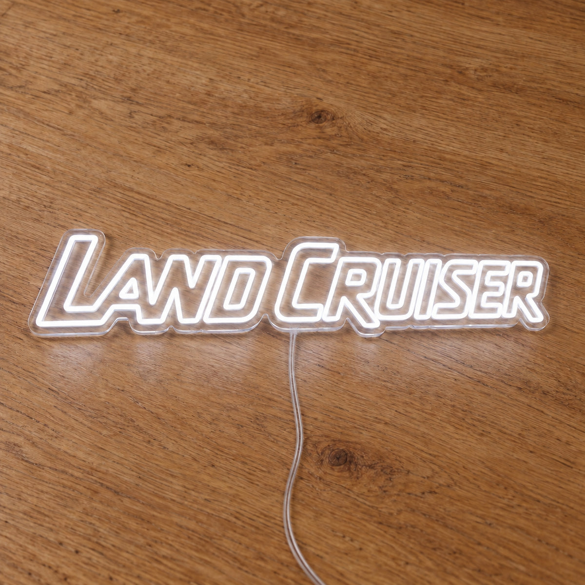 Toyota Land Cruiser LED Neon Sign in white, featuring Land Cruiser lettering on a wooden surface.