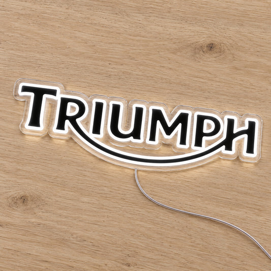 Triumph LED Neon Sign, featuring illuminated vehicle logo on a wooden surface.