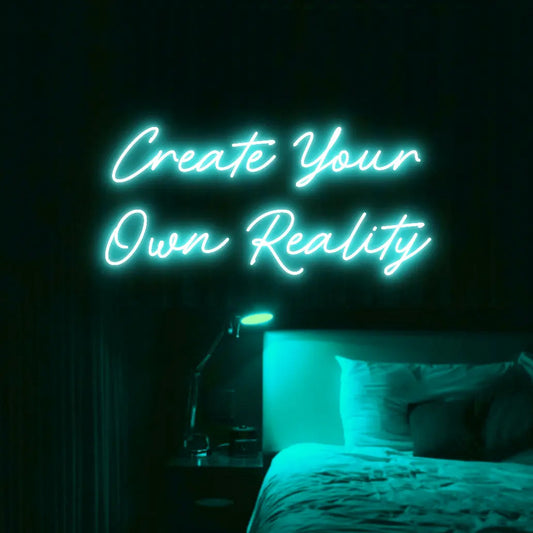 Create Your Own Reality LED Neon Light Sign in turquoise, featuring two lines of script lettering illuminated above a bed.