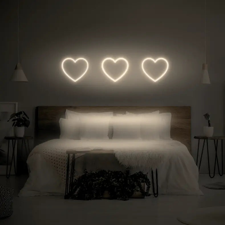 3 Hearts LED Neon Light Sign in warm white, featuring three heart outlines illuminated above a bed.