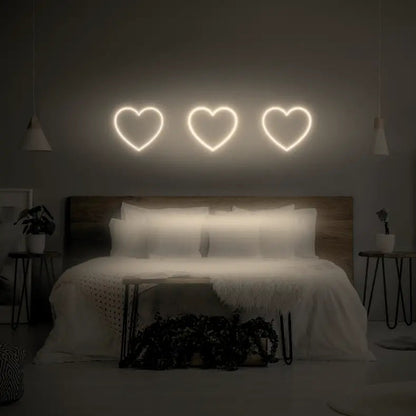 3 Hearts LED Neon Light Sign in warm white, featuring three heart outlines illuminated above a bed.