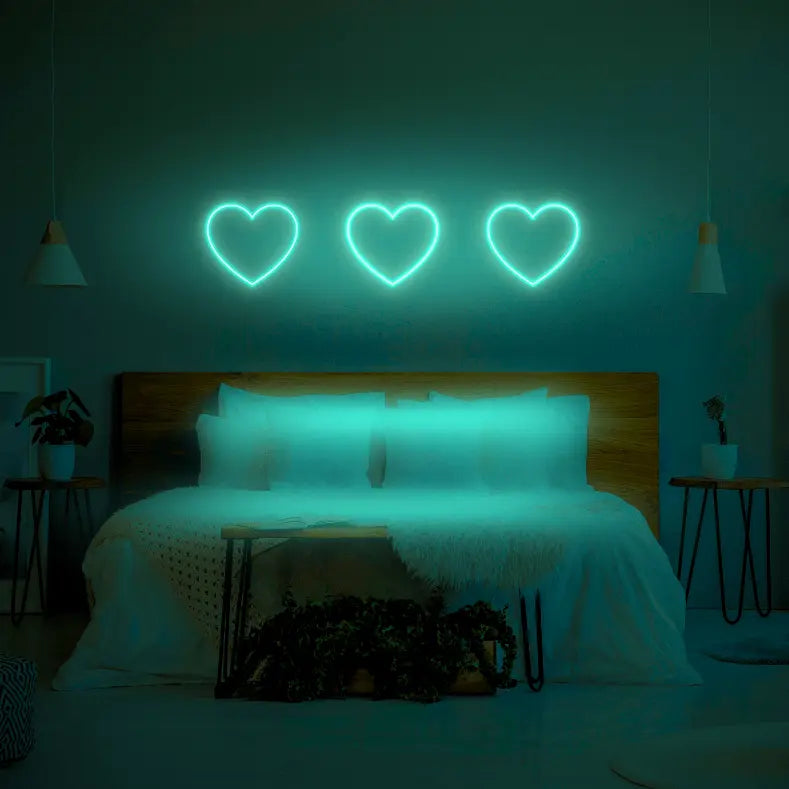 3 Hearts LED Neon Light Sign in green, featuring three heart outlines illuminated above a bed.