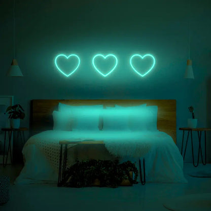 3 Hearts LED Neon Light Sign in green, featuring three heart outlines illuminated above a bed.
