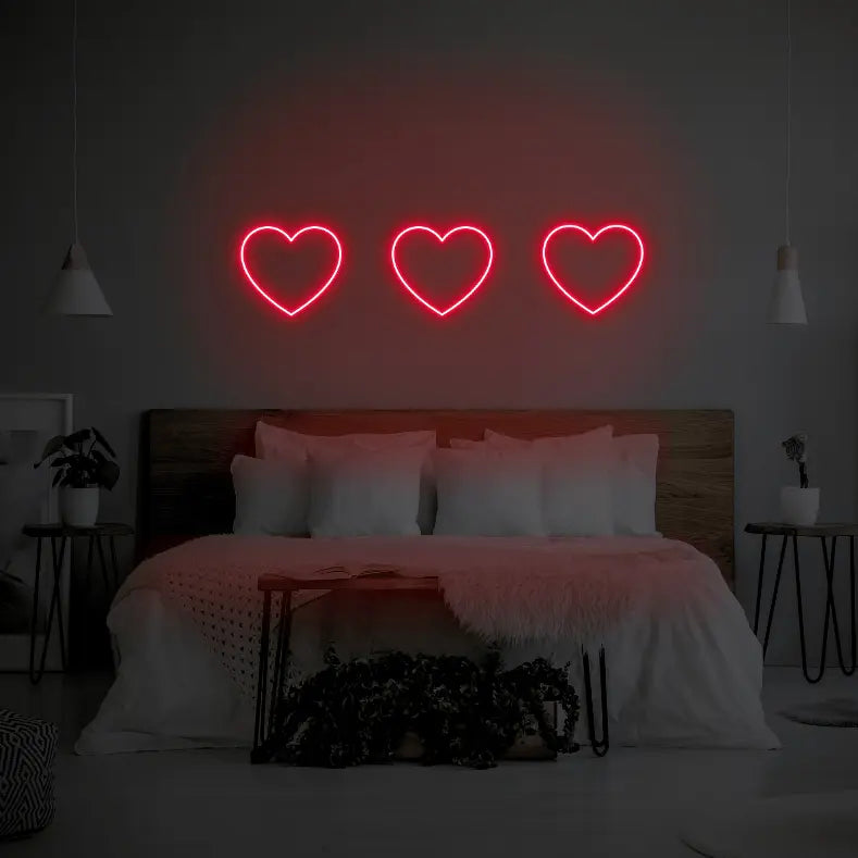 3 Hearts LED Neon Light Sign in red, featuring three heart outlines illuminated above a bed.