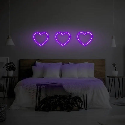 3 Hearts LED Neon Light Sign in purple, featuring three heart outlines illuminated above a bed.