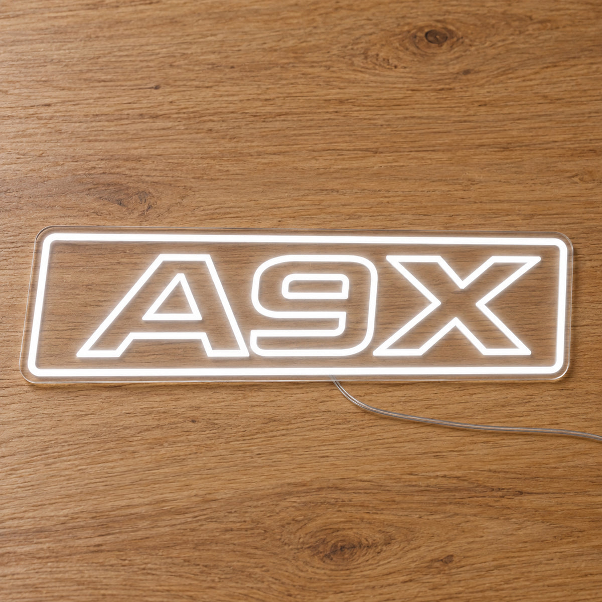 A9X Torana LED Neon Sign in white, featuring A9X lettering inside a rectangular border on a wooden surface.