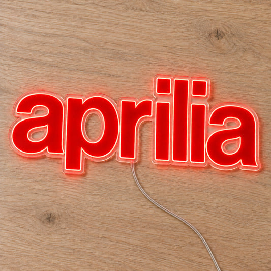 Aprilia LED Neon Sign, featuring illuminated vehicle logo on a wooden surface.