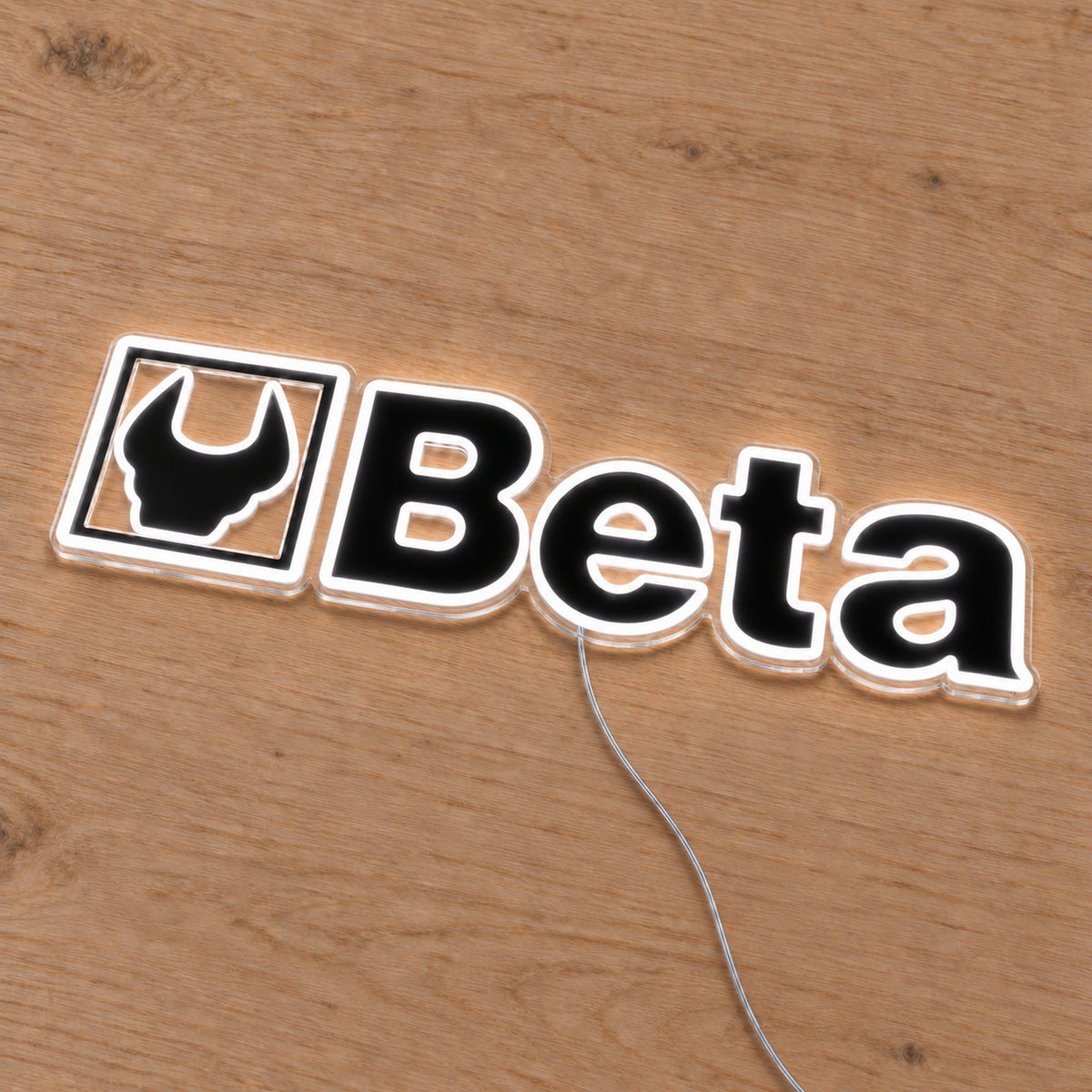 Beta LED Neon Sign, featuring illuminated vehicle logo on a wooden surface viewed at an angle.
