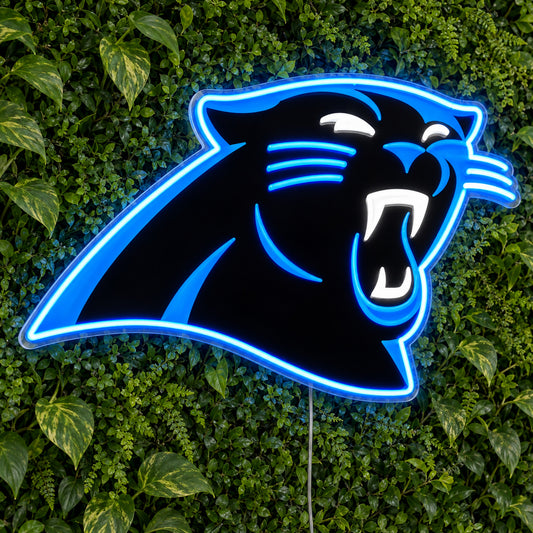 Carolina Panthers LED Neon Sign, featuring illuminated team logo on a green foliage wall.