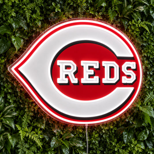Cincinnati Reds LED Neon Sign, featuring illuminated team logo on a green foliage wall.