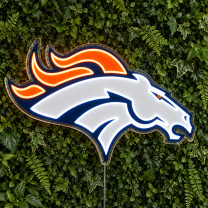 Denver Broncos LED Neon Sign, featuring illuminated team logo on a green foliage wall.