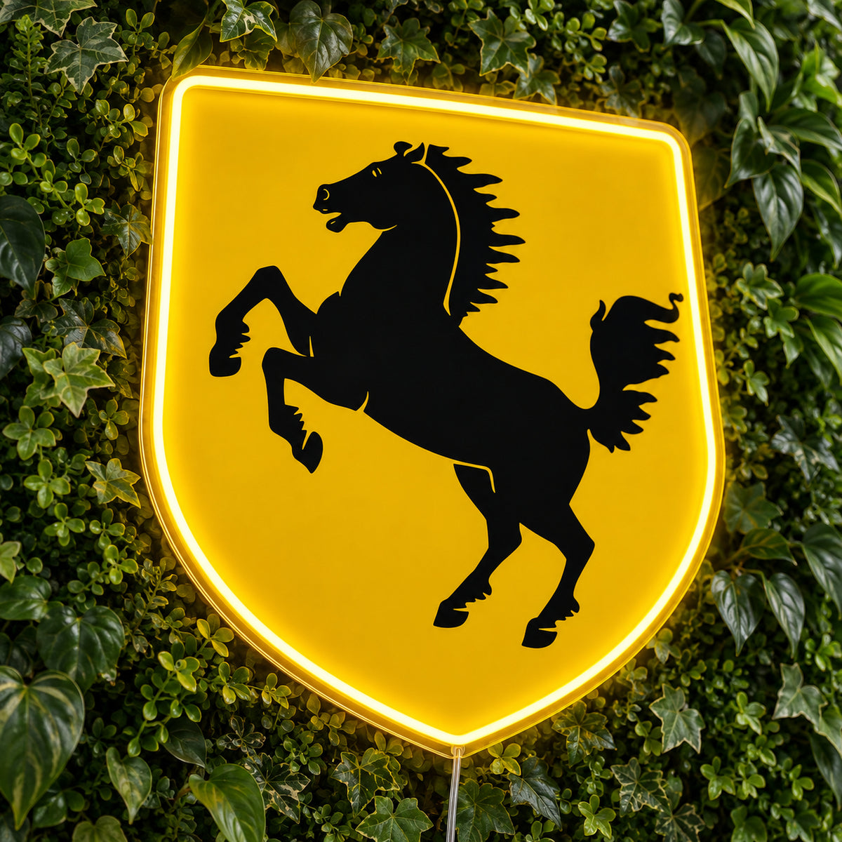 Ferrari Shield LED Neon Sign, featuring vehicle-brand emblem displayed on a green foliage wall.