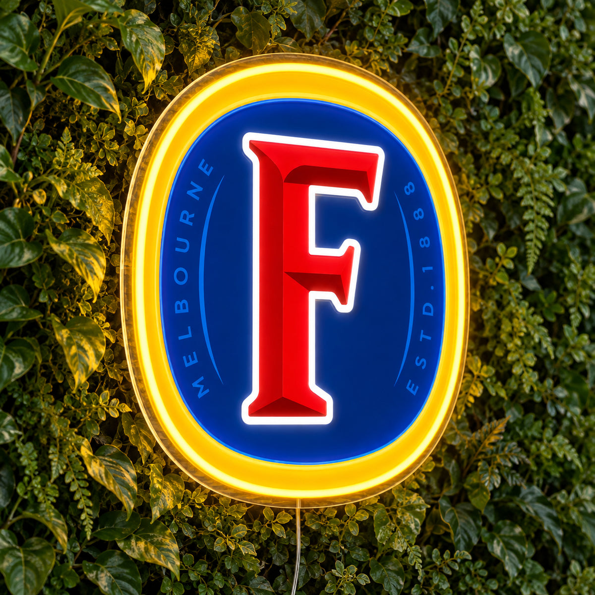 Fosters LED Neon Sign, featuring beer-brand logo displayed on a green foliage wall.