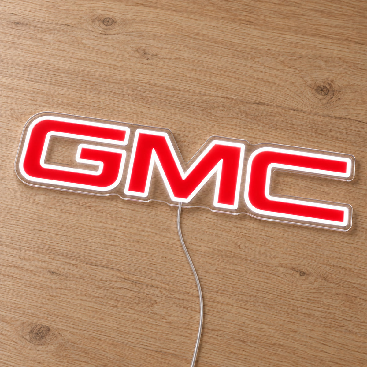 GMC LED Neon Sign, featuring illuminated vehicle logo on a wooden surface.