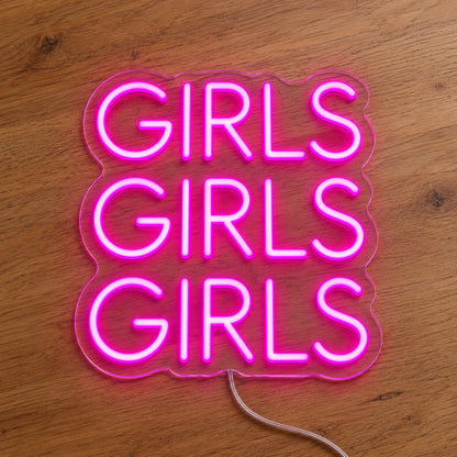 Girls LED Neon Sign in pink, featuring three stacked words on a wooden surface.