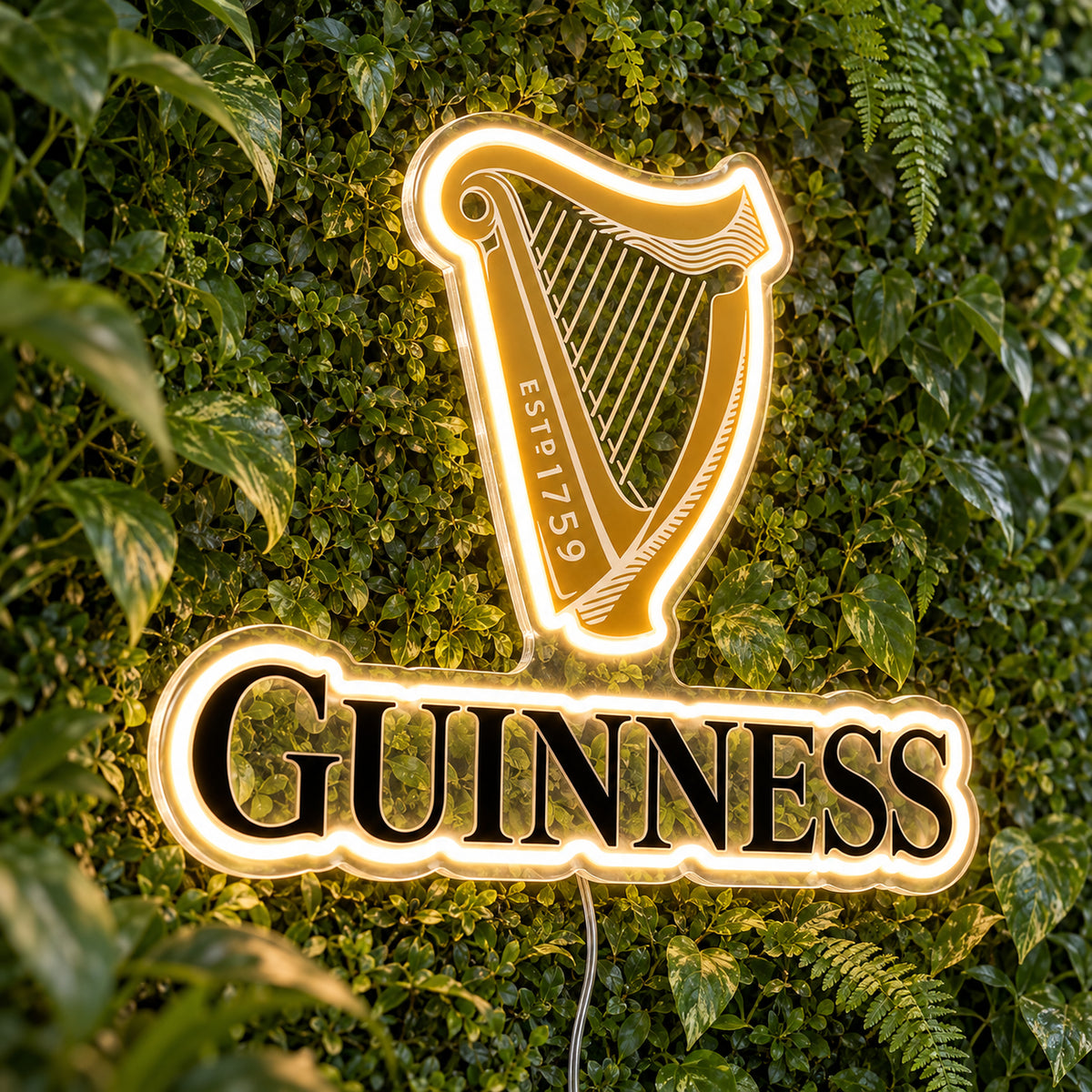 Guinness LED Neon Sign, featuring beer-brand logo displayed on a green foliage wall.