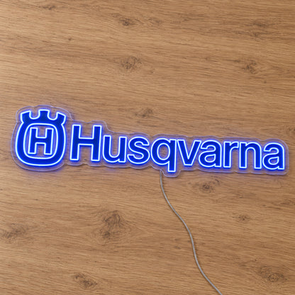 Husqvarna LED Neon Sign, featuring illuminated vehicle logo on a wooden surface.
