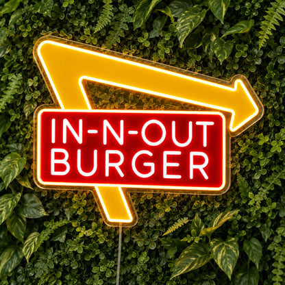 In-N-Out Burger LED Neon Sign, featuring illuminated brand logo on a green foliage wall.