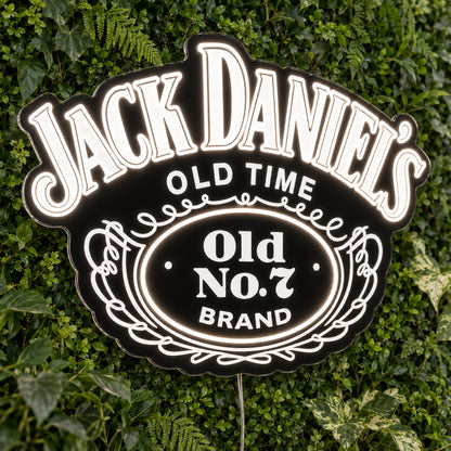Jack Daniels LED Neon Sign, featuring illuminated brand logo on a green foliage wall.