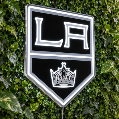 Los Angeles Kings LED Neon Sign, featuring team logo displayed on a green foliage wall.