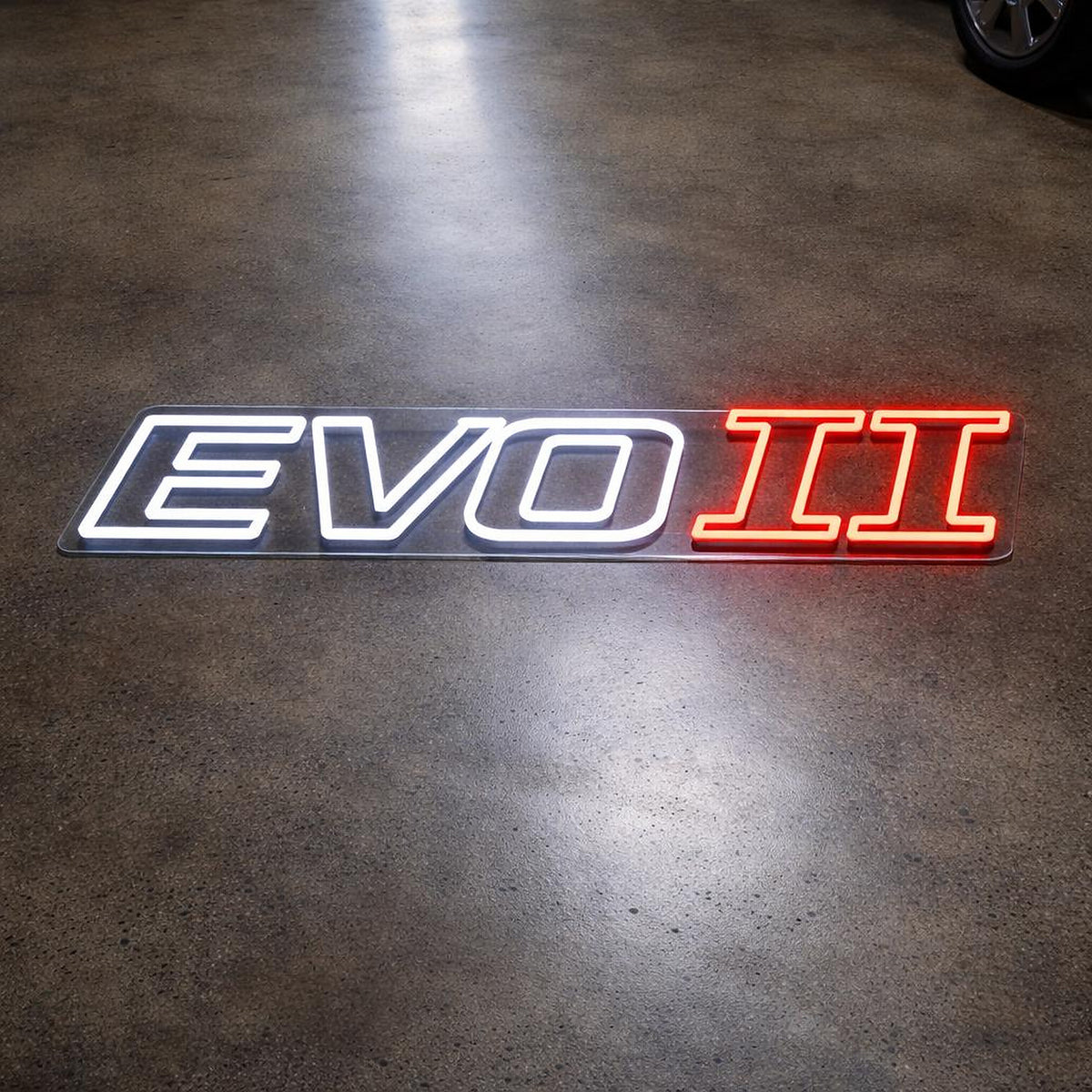 Lancer Evo II LED Neon Sign in white and red, featuring Evo II lettering on a dark wooden surface.