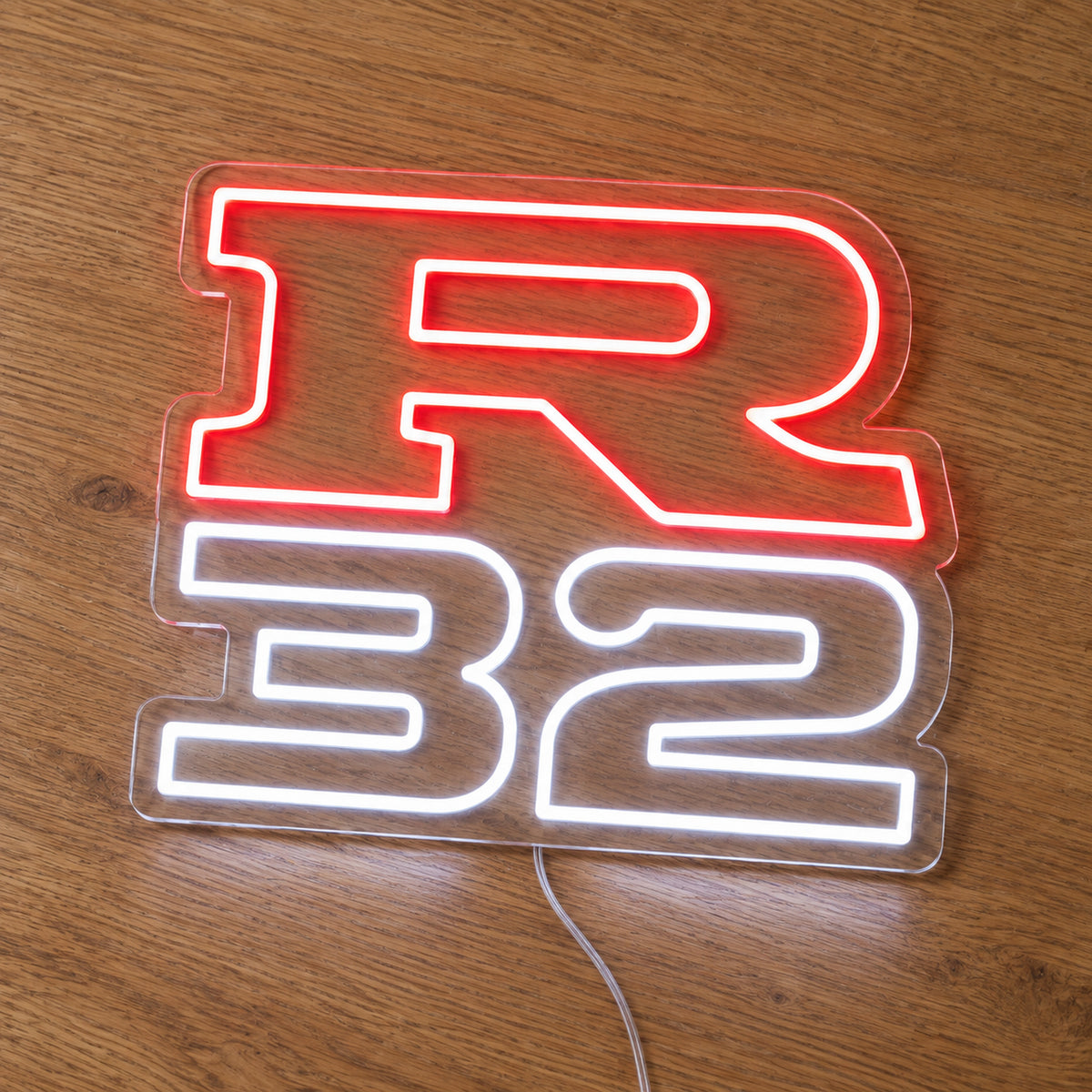 Nissan R32 LED Neon Sign in red and white, featuring R32 lettering on a wooden surface.