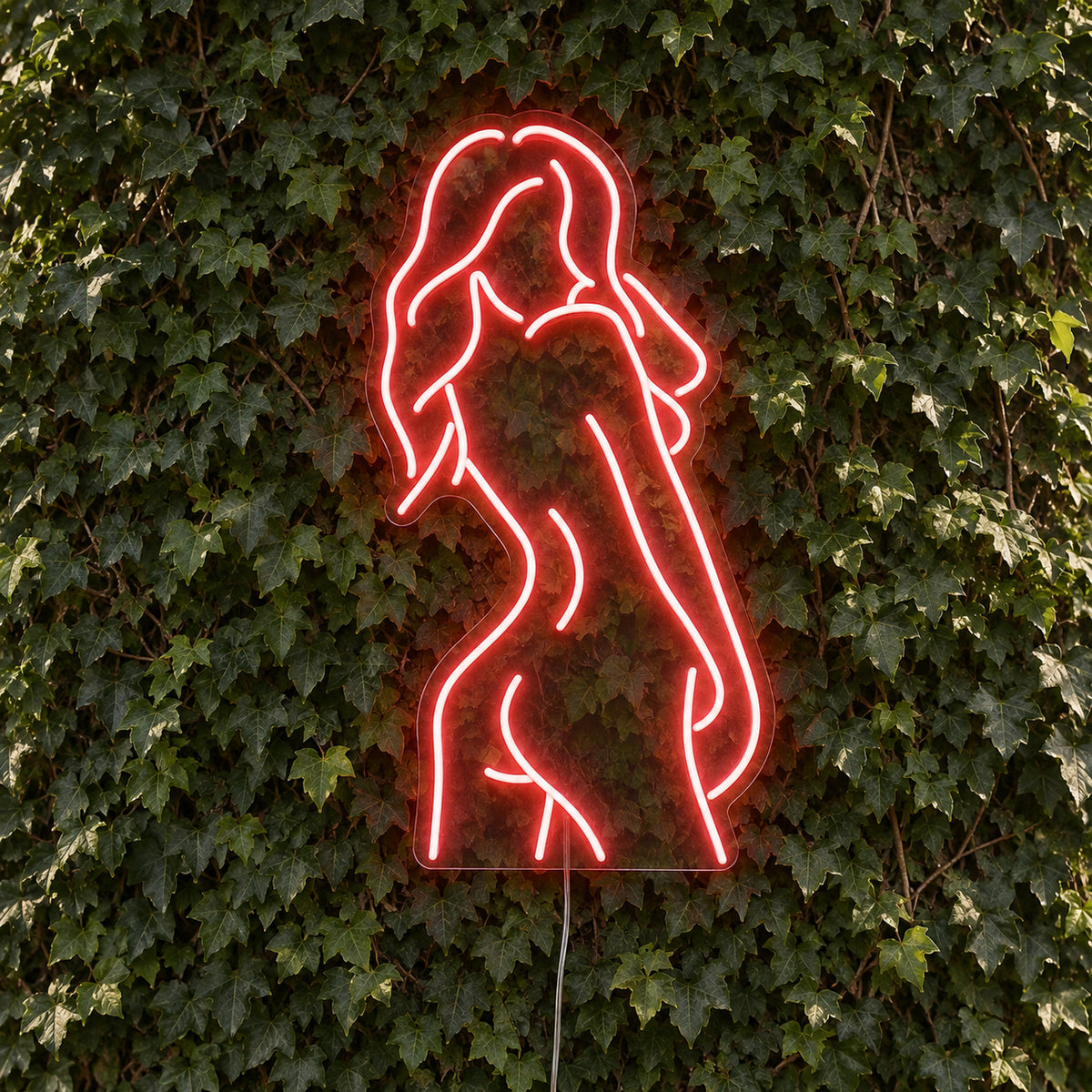 Nude Woman LED Neon Sign in red, featuring outline of a woman's figure against a foliage wall.