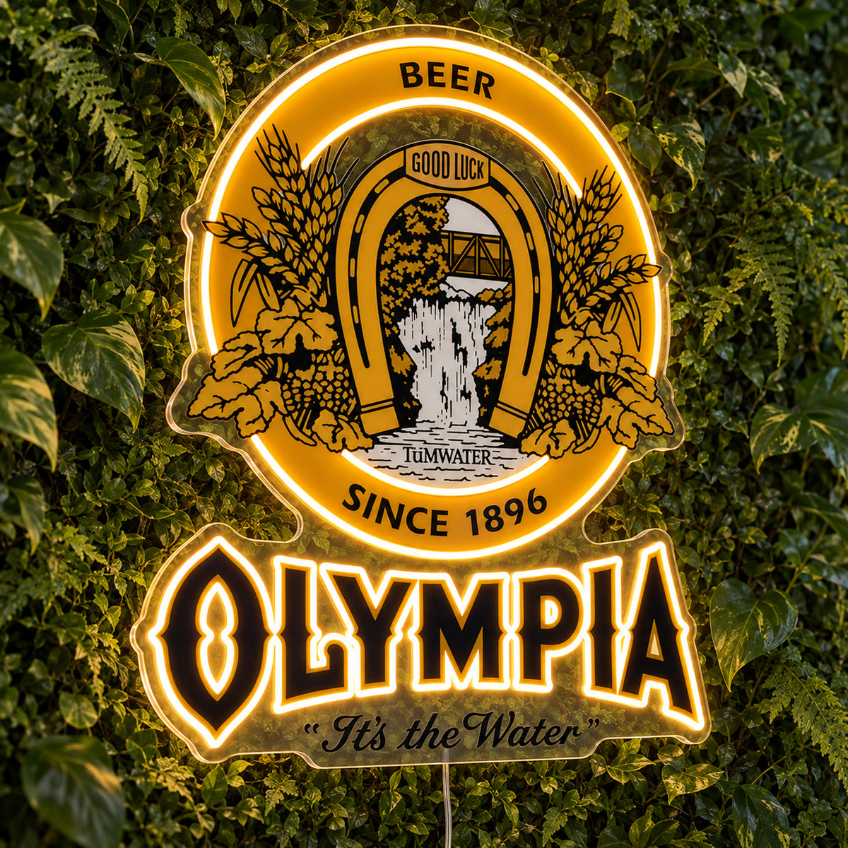 Olympia LED Neon Sign, featuring beer-brand logo displayed on a green foliage wall.