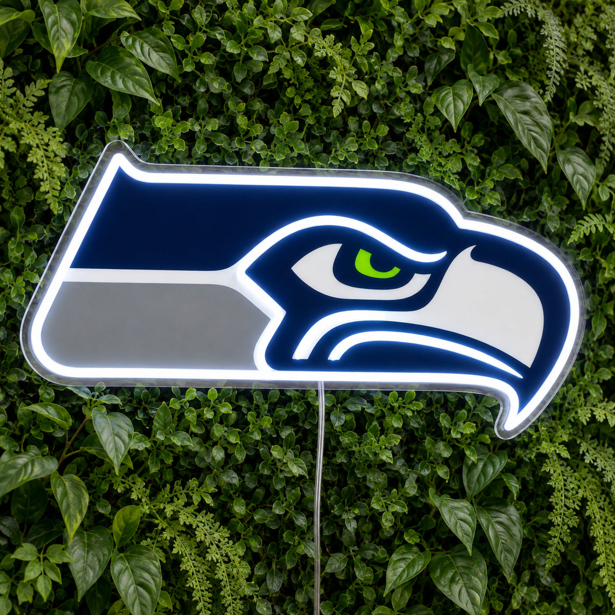 Seattle Seahawks LED Neon Sign, featuring illuminated team logo on a green foliage wall.