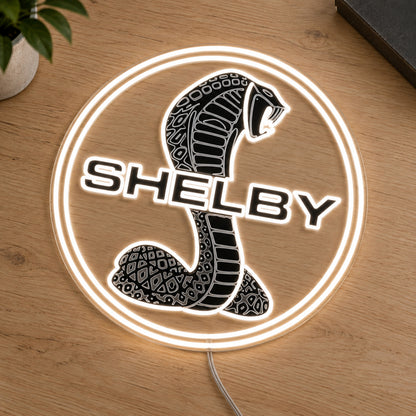 Shelby Cobra LED Neon Sign, featuring illuminated vehicle logo on a wooden surface.