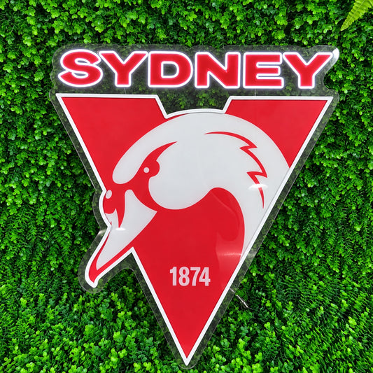 Sydney Swans LED Neon Sign, featuring illuminated team logo on a green foliage wall.