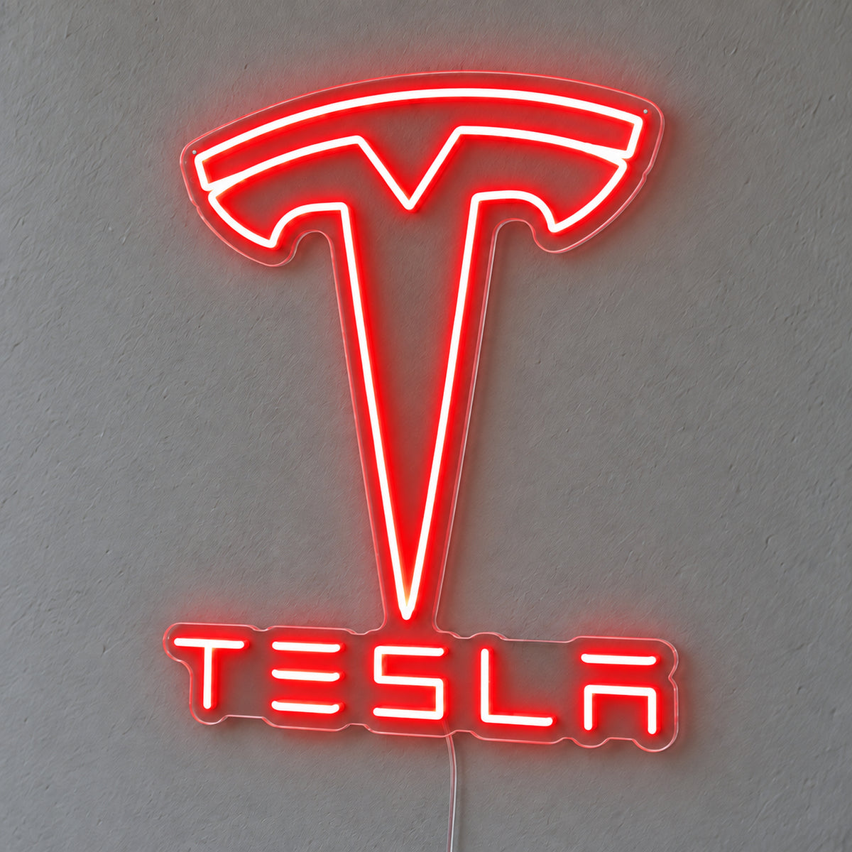 Tesla LED Neon Sign in red, featuring the Tesla emblem and lettering on a grey wall.
