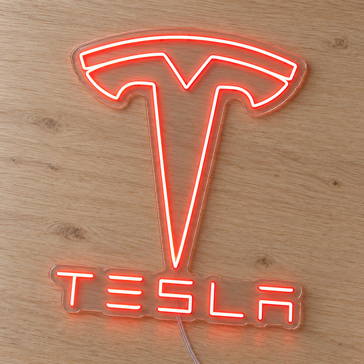 Tesla LED Neon Sign in red, featuring the Tesla emblem and lettering on a wooden surface.