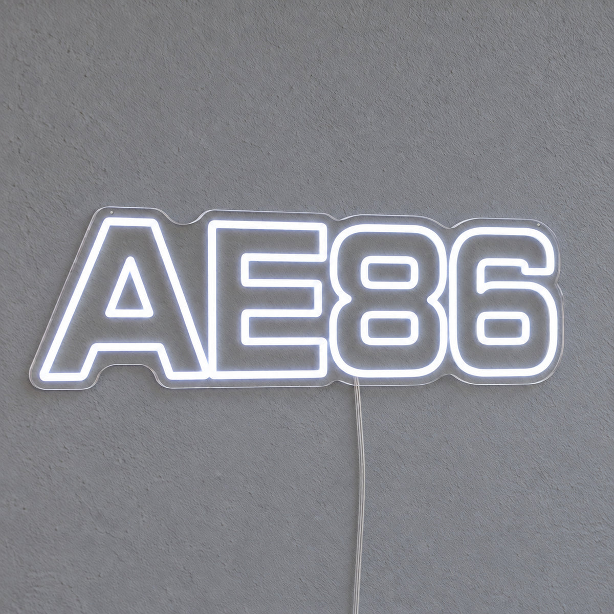 Toyota AE86 LED Neon Sign in white, featuring AE86 lettering on a grey wall.