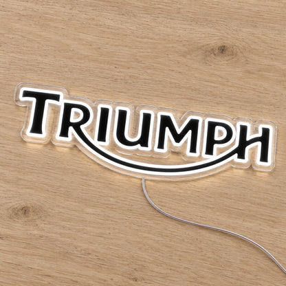 Triumph LED Neon Sign, featuring illuminated vehicle logo on a wooden surface.