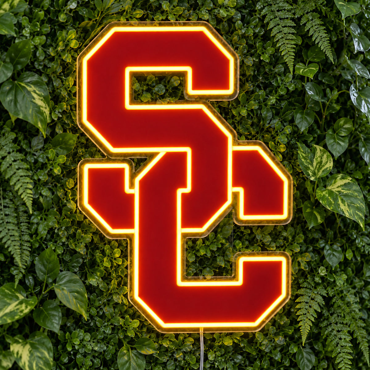 USC Trojans LED Neon Sign, featuring team logo displayed on a green foliage wall.