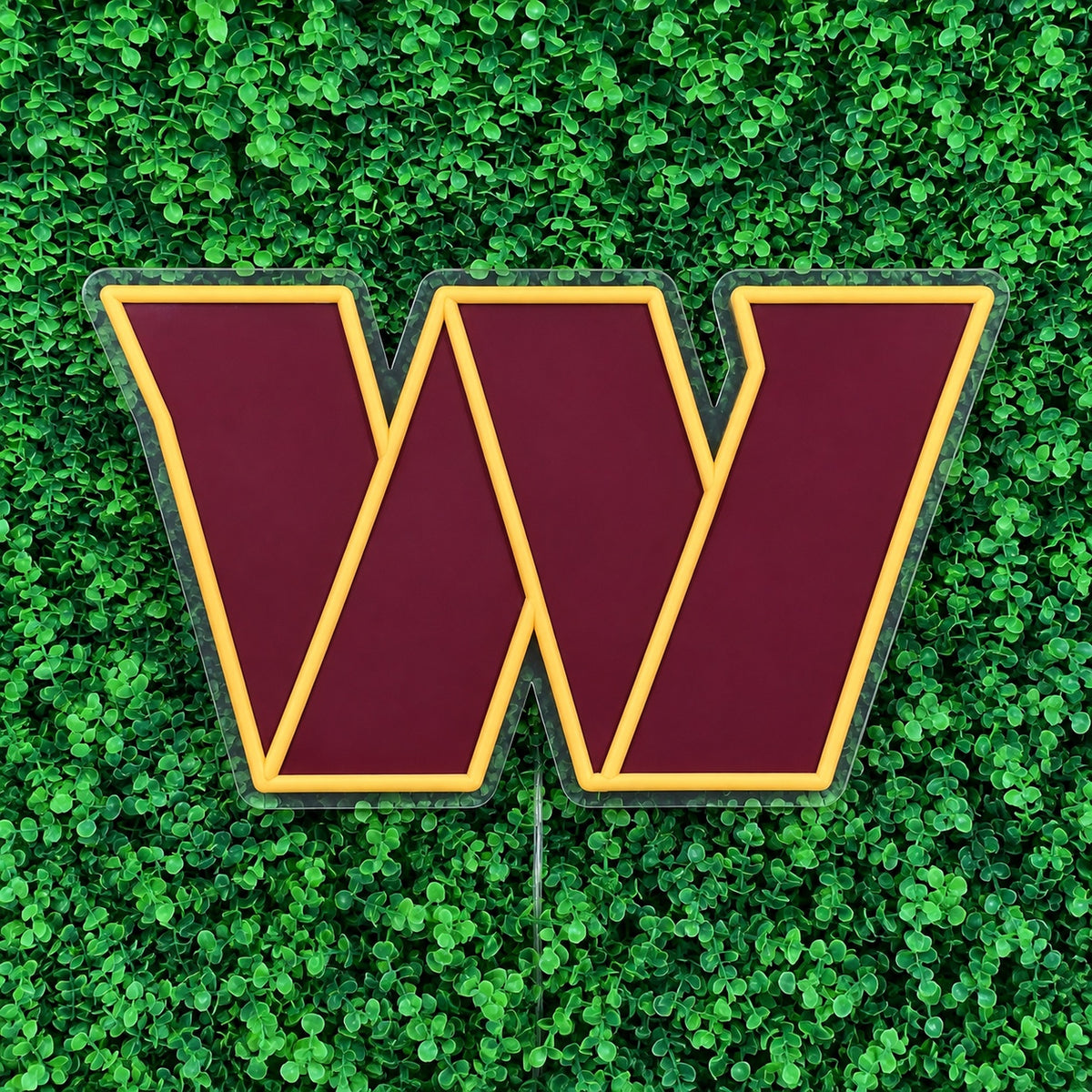 Washington Commanders LED Neon Sign, featuring team W emblem against green foliage, with the sign switched off.