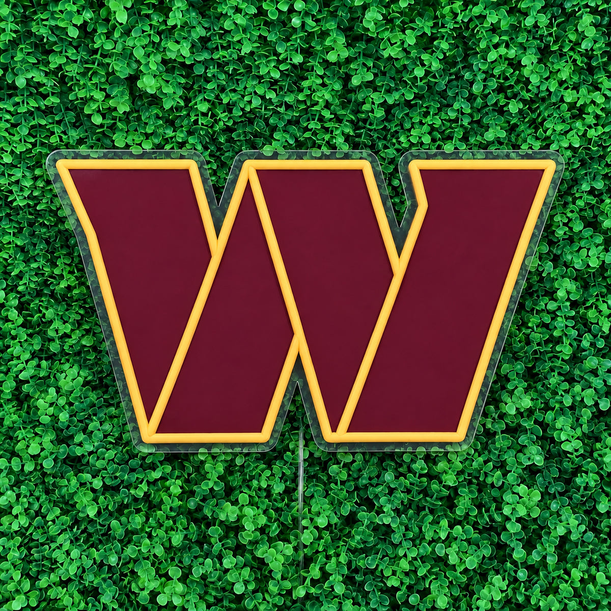 Washington Commanders LED Neon Sign, featuring team W emblem against green foliage, viewed at an angle.