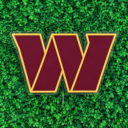 Washington Commanders LED Neon Sign, featuring team W emblem against green foliage, viewed at an angle.