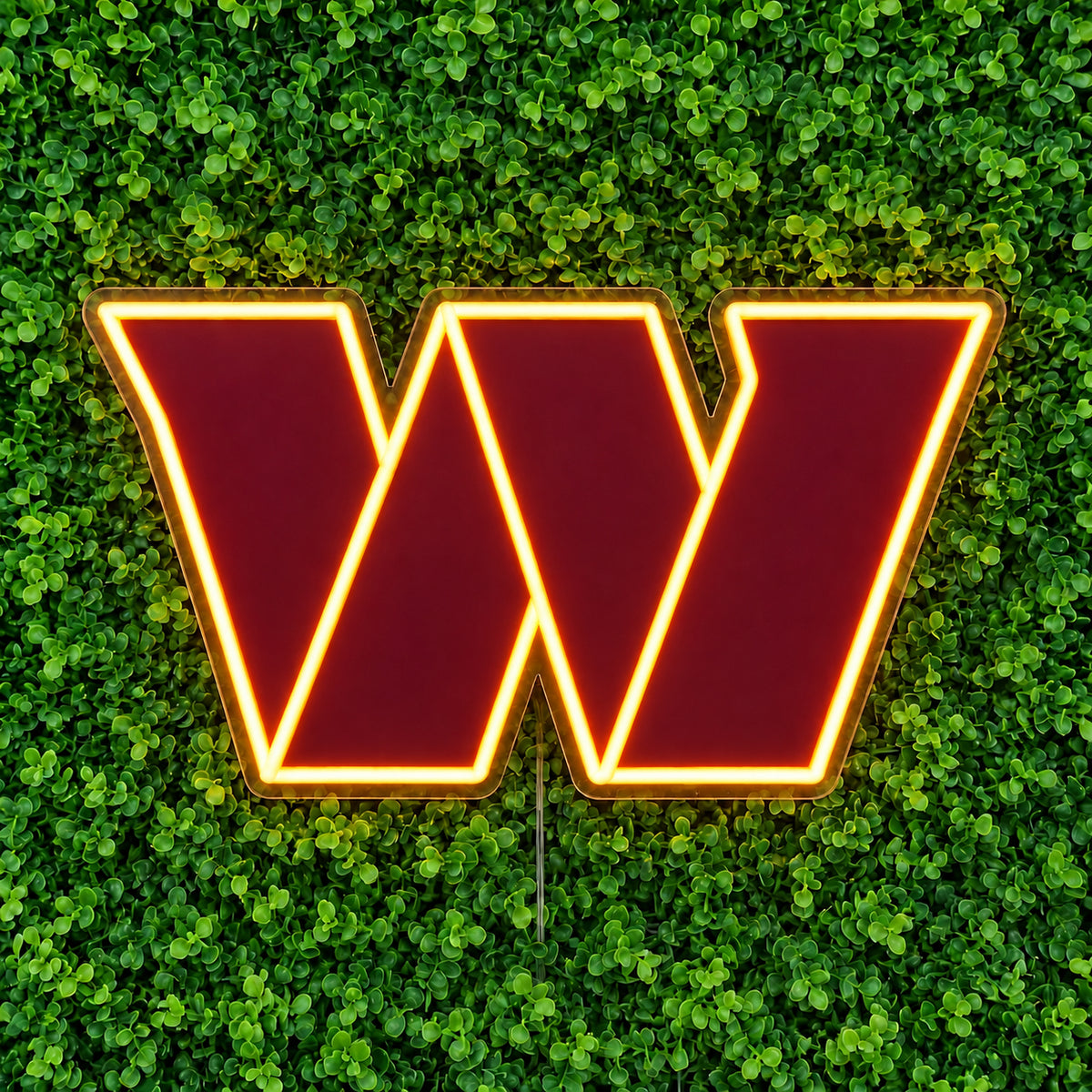 Washington Commanders LED Neon Sign, featuring illuminated team logo on a green foliage wall.