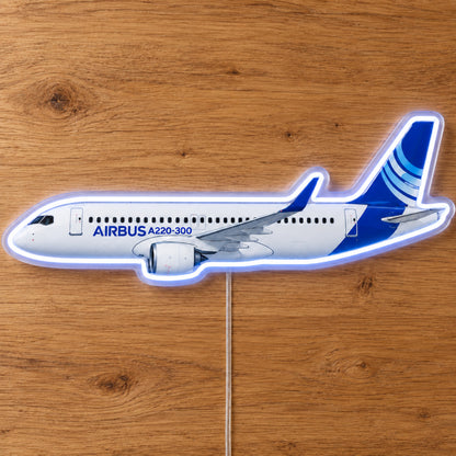 Airbus A220 Neon Sign with printed aircraft details and an illuminated LED outline on clear acrylic, shown on a wooden surface