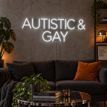 Autistic & Gay Neon Sign glowing white above a dark sofa against a concrete wall.