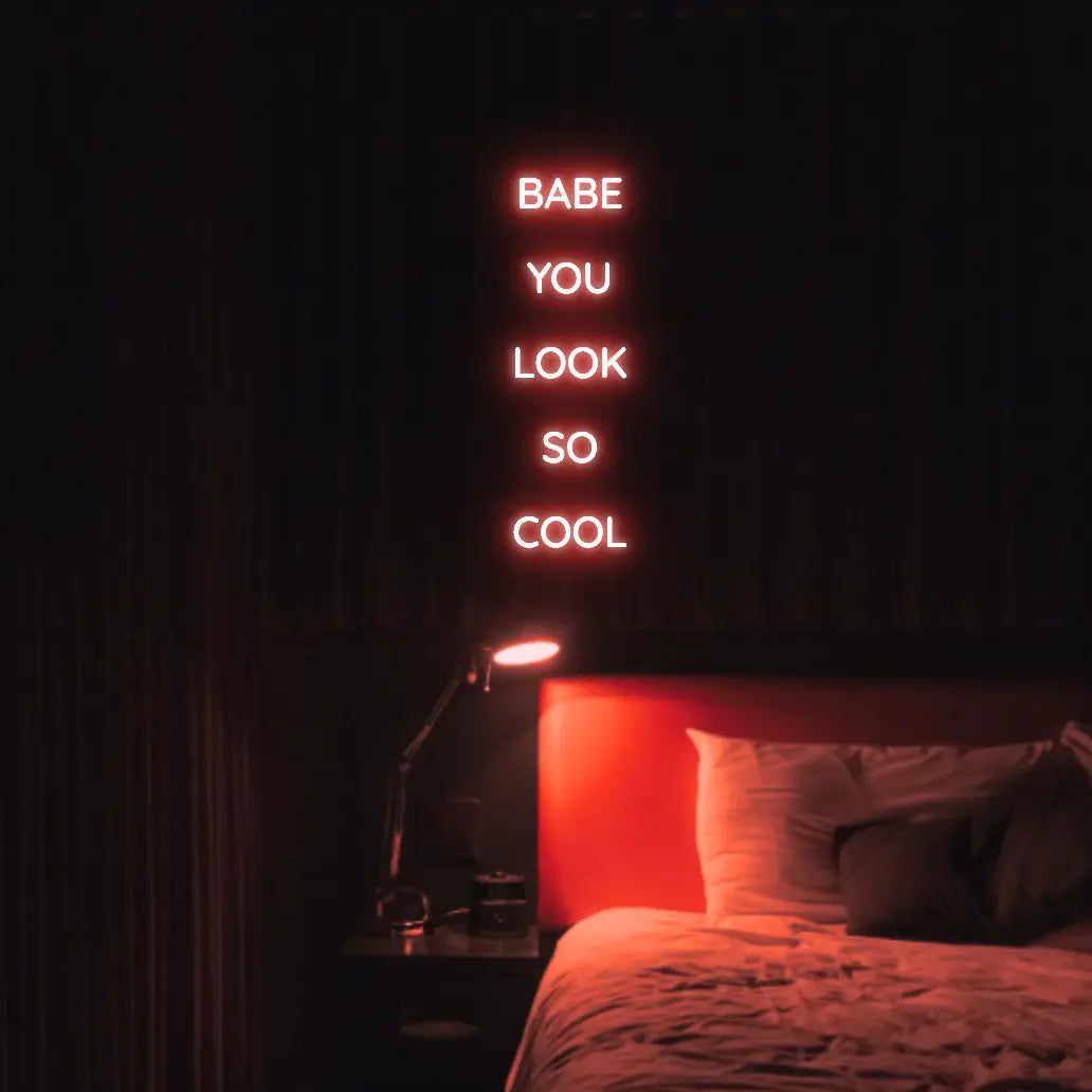 Babe You Look So Cool 2 LED Neon Light Sign in red, featuring five stacked words illuminated above a bed.